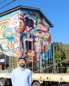 コウノトリの翼をモチーフにした壁面画と大山康太郎さん=豊岡市中央町 コウノトリの翼をモチーフにした壁面画と大山康太郎さん=豊岡市中央町