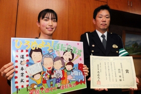 交通安全ポスターコンクールで県知事賞に輝き、美方署員から表彰を受けた岡田華さん(左)=夢が丘中 交通安全ポスターコンクールで県知事賞に輝き、美方署員から表彰を受けた岡田華さん(左)=夢が丘中