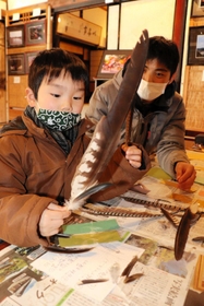 鳥の羽根を使ったしおり作りに挑戦する子ども=新温泉町浜坂 鳥の羽根を使ったしおり作りに挑戦する子ども=新温泉町浜坂