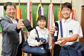 消毒スプレー用の携帯ホルダーを服部清隆社長(左)から受け取った齊藤雛嬉さん(中央)と左右田莉玖さん=豊岡北中 消毒スプレー用の携帯ホルダーを服部清隆社長(左)から受け取った齊藤雛嬉さん(中央)と左右田莉玖さん=豊岡北中
