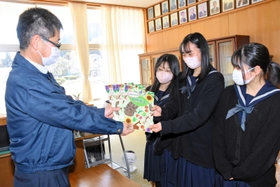 梶原秀規校長に自然図鑑を手渡す生野高生の3人=山口小学校 梶原秀規校長に自然図鑑を手渡す生野高生の3人=山口小学校