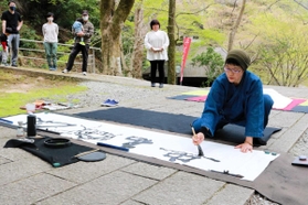 疫病終息や世界平和を願って書をしたためる大西真來さん=石龕寺 疫病終息や世界平和を願って書をしたためる大西真來さん=石龕寺