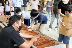 職人に教わりながら檜皮に竹くぎを打ち込む子どもたち=丹波市山南町篠場、山南ふるさと文化財の森センター 職人に教わりながら檜皮に竹くぎを打ち込む子どもたち=丹波市山南町篠場、山南ふるさと文化財の森センター