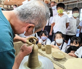 児童を前に、ろくろによる器作りを実演する大上巧さん(手前)=大熊窯 児童を前に、ろくろによる器作りを実演する大上巧さん(手前)=大熊窯