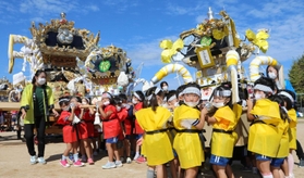 大人屋台(左奥)の近くで段ボール屋台を練る園児=川西小学校 大人屋台(左奥)の近くで段ボール屋台を練る園児=川西小学校
