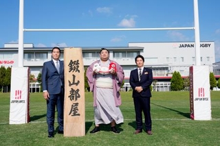 錣山部屋が宿舎を構えることになった日本ラグビー協会の強化拠点「ジャパンベース」で記念撮影する(左から)錣山親方と阿炎ら=27日、福岡市