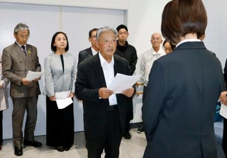 山口県上関町役場で、担当職員(手前)に申し入れ書を提出する議連幹事長の小中進田布施町議(中央)ら=29日午後