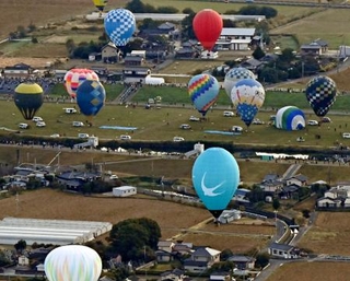 佐賀インターナショナルバルーンフェスタが開幕し、浮かび上がる熱気球=30日午前、佐賀市(共同通信社ヘリから)