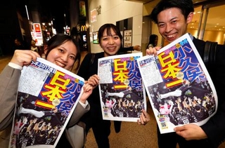 ソフトバンクの日本一を伝える号外を手に笑顔の人たち=30日夜、福岡市