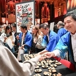 「ジャパンエキスポ」で来場者に天むすを配る名古屋市の広沢一郎市長(右端)=25日、オーストラリア・シドニー(共同)