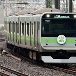 環状運転100周年記念のヘッドマークを付け走行するJR山手線のラッピング列車=25日午後、東京都渋谷区