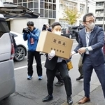 「サクセス観光」事務所からの押収物を運ぶ北海道警の捜査員=23日、札幌市中央区