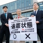 「1票の格差」訴訟の判決を受け、名古屋高裁金沢支部前で「違憲状態」などと書かれた紙を掲げる原告側の升永英俊弁護士(中央)ら=29日午後