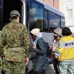 北海道電力泊原発3号機の重大事故を想定した防災訓練で、自衛隊員運転のバスに乗り込む住民=29日午前、北海道積丹町