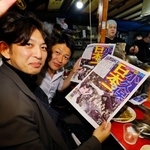 ソフトバンクの日本一を伝える号外を手に、福岡・天神の屋台で喜ぶ客=30日夜