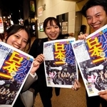 ソフトバンクの日本一を伝える号外を手に笑顔の人たち=30日夜、福岡市