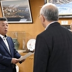 北海道泊村議会の議長らから意見書を受け取る高橋鉄徳村長(左)=31日午前、北海道泊村