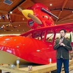 リニューアルされたカフェ「ロタンダ風ケ丘」で、映画「紅の豚」に登場する赤い飛行艇を再現した作品を紹介するジブリパークの宮崎吾朗監督=31日午前、愛知県長久手市