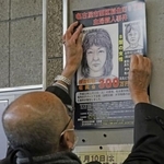 名鉄上小田井駅で情報提供を求めるポスターを張る高羽奈美子さんの夫悟さん=2月、名古屋市