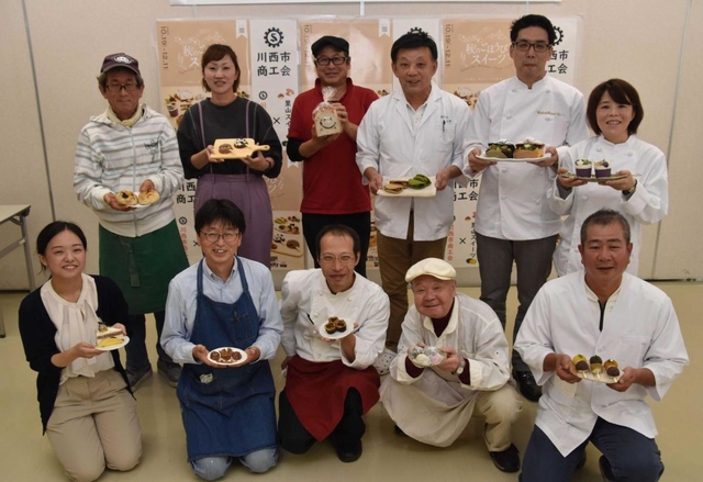 創作した「秋のごほうびスイーツ」を持つ参加店の店主ら=川西市出在家町