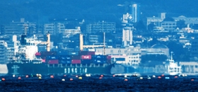 超望遠レンズでのぞくと明石海峡付近の海面は盛り上がって見える。天文科学館は灯台のようだ=淡路市富島から(撮影・三津山朋彦) 超望遠レンズでのぞくと明石海峡付近の海面は盛り上がって見える。天文科学館は灯台のようだ=淡路市富島から(撮影・三津山朋彦)