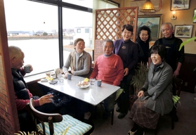 大きな窓の外には、ため池が広がる。常連客とマスターの的野城己さん(最後列右)と春江さん(同左)=珈琲工房「華鈴」 大きな窓の外には、ため池が広がる。常連客とマスターの的野城己さん(最後列右)と春江さん(同左)=珈琲工房「華鈴」