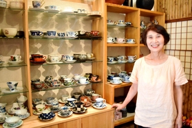 自慢の器が並ぶ棚と、店主の北川伊久子さん=神戸市垂水区神田町4 自慢の器が並ぶ棚と、店主の北川伊久子さん=神戸市垂水区神田町4