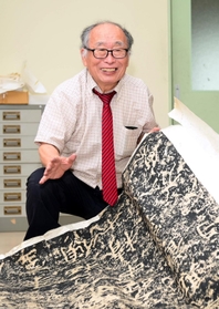 鄭道昭の拓本を広げ、目を細める牛丸好一さん。「風土の中に生きる古典の原石を見ると畏怖の念を覚えます」=神戸市中央区、神戸市立葺合高校(撮影・坂井萌香) 鄭道昭の拓本を広げ、目を細める牛丸好一さん。「風土の中に生きる古典の原石を見ると畏怖の念を覚えます」=神戸市中央区、神戸市立葺合高校(撮影・坂井萌香)