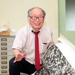 鄭道昭の拓本を広げ、目を細める牛丸好一さん。「風土の中に生きる古典の原石を見ると畏怖の念を覚えます」=神戸市中央区、神戸市立葺合高校(撮影・坂井萌香)