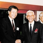 1964年の東京五輪実現に尽力したフレッド・和田勇さん(右)と握手する高杉良さん。「祖国へ、熱き心を」に結実した=1990年4月、東京・内幸町(高杉さん提供)