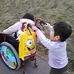 お姉ちゃんの車いすを押すコウタ(右)。車輪がミッキーマウスの柄で、かっこいい!と思っていたんだって(提供写真)