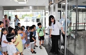 自動ドアの戸袋部分に指が挟まれる危険性を子どもたちに説明する岡真裕美さん=神戸市東灘区魚崎浜町 自動ドアの戸袋部分に指が挟まれる危険性を子どもたちに説明する岡真裕美さん=神戸市東灘区魚崎浜町