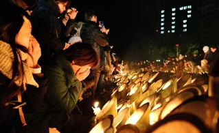 竹灯籠のろうそくに涙ながら祈りをささげる女性17日午前5時57分、神戸市中央区加納町6、東遊園地