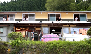 北田茜さん(23)=手前中央=は今春、但馬の山深い集落にある廃業した元民宿に移住した。宿の復活を目指し、布団干し作業の手伝いをSNSなどで呼び掛けたところ、県内から十数人が集結。地元も「よぉ来てくれた」と歓迎ムードで、山あいに歓声が響き笑顔があふれた=兵庫県香美町小代区貫田