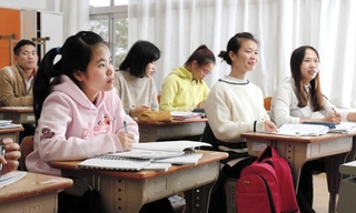 2010年に閉校した旧仁井小学校の教室で授業を受ける、東南アジアからの留学生。真剣な表情で懸命にペンを走らせる=淡路市仁井、「日本グローバルアカデミー」
