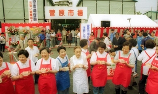 仮設店舗での再開。祝い酒を手に喜ぶ人たち=1995年5月25日、神戸市長田区菅原通