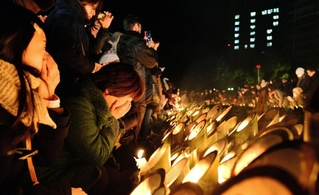 竹灯籠のろうそくに涙ながら祈りをささげる女性17日午前5時57分、神戸市中央区加納町6、東遊園地