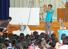 「水」をテーマにした実験を全校児童の前で次々と披露する中田真一先生(右)=尼崎市七松町1、七松小学校(撮影・小林良多) 「水」をテーマにした実験を全校児童の前で次々と披露する中田真一先生(右)=尼崎市七松町1、七松小学校(撮影・小林良多)