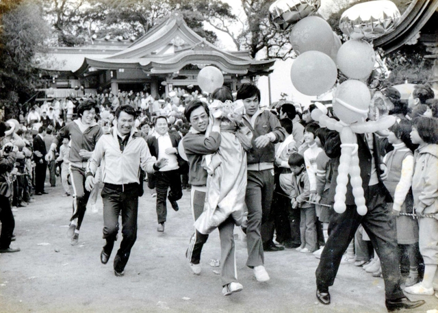 以前は由良湊神社からお旅所まで一番乗りを目指し、子どもを担いで全力で走った=1979年2月15日(伊富貴江利さん提供)、洲本市由良 以前は由良湊神社からお旅所まで一番乗りを目指し、子どもを担いで全力で走った=1979年2月15日(伊富貴江利さん提供)、洲本市由良