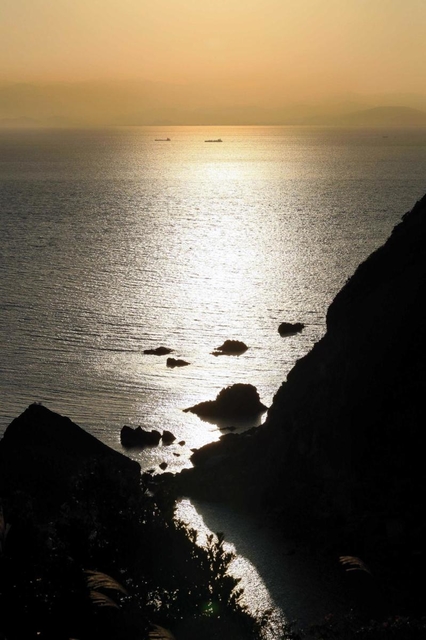 夕日に映える沼島の南側。遠く四国がかすんで見える=南あわじ市沼島 夕日に映える沼島の南側。遠く四国がかすんで見える=南あわじ市沼島
