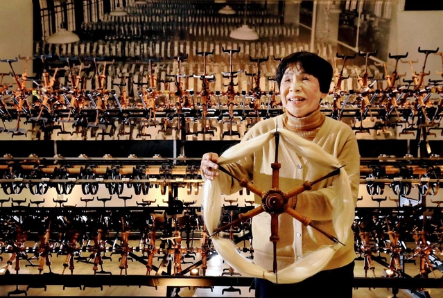 生糸の強度を測る機器を手に思い出を語る宮垣貴美代さん。奥に掲げられた機器の写真パネルが、生糸検査所の華やかな時代をしのばせる=神戸市中央区小野浜町(撮影・大山伸一郎) 生糸の強度を測る機器を手に思い出を語る宮垣貴美代さん。奥に掲げられた機器の写真パネルが、生糸検査所の華やかな時代をしのばせる=神戸市中央区小野浜町(撮影・大山伸一郎)
