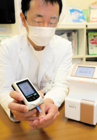 血糖値を測る機械で検査を実演する中村武寛部長とヘモグロビンA1cを計測できる機械(右)=神戸市長田区一番町2、市立医療センター西市民病院 血糖値を測る機械で検査を実演する中村武寛部長とヘモグロビンA1cを計測できる機械(右)=神戸市長田区一番町2、市立医療センター西市民病院
