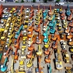 約2万2千平方メートルの敷地に並んだ中古建機。洗車や検品を済ませ、オークションを待つばかり(小型無人機より撮影)=神戸市中央区港島8