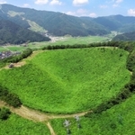 夏は緑、冬は銀世界に染まる神鍋山噴火口。後方の山の斜面は奥神鍋スキー場(小型無人機より撮影)=豊岡市日高町栗栖野