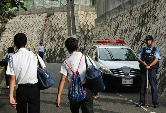 登校する中学生を見守る警察官=27日午前、神戸市中央区