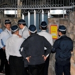 仮命令を出すため山口組総本部に集まった捜査員。赤と黄色の「使用制限」の標章が玄関に張られた=12日未明、神戸市灘区篠原本町4