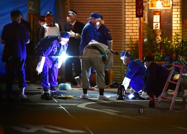 射殺事件があった現場付近を調べる兵庫県警の捜査員=27日夜、尼崎市神田南通1