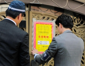 山口組の総本部で、使用制限を示す「標章」を仮命令用から本命令用に張り替える兵庫県警の警察官=15日、神戸市灘区篠原本町4 山口組の総本部で、使用制限を示す「標章」を仮命令用から本命令用に張り替える兵庫県警の警察官=15日、神戸市灘区篠原本町4