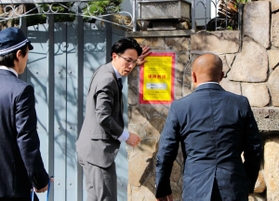 山口組の総本部で、使用制限を示す「標章」を仮命令用から本命令用に張り替える兵庫県警の警察官=15日、神戸市灘区篠原本町4 山口組の総本部で、使用制限を示す「標章」を仮命令用から本命令用に張り替える兵庫県警の警察官=15日、神戸市灘区篠原本町4