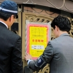 山口組の総本部で、使用制限を示す「標章」を仮命令用から本命令用に張り替える兵庫県警の警察官=15日、神戸市灘区篠原本町4